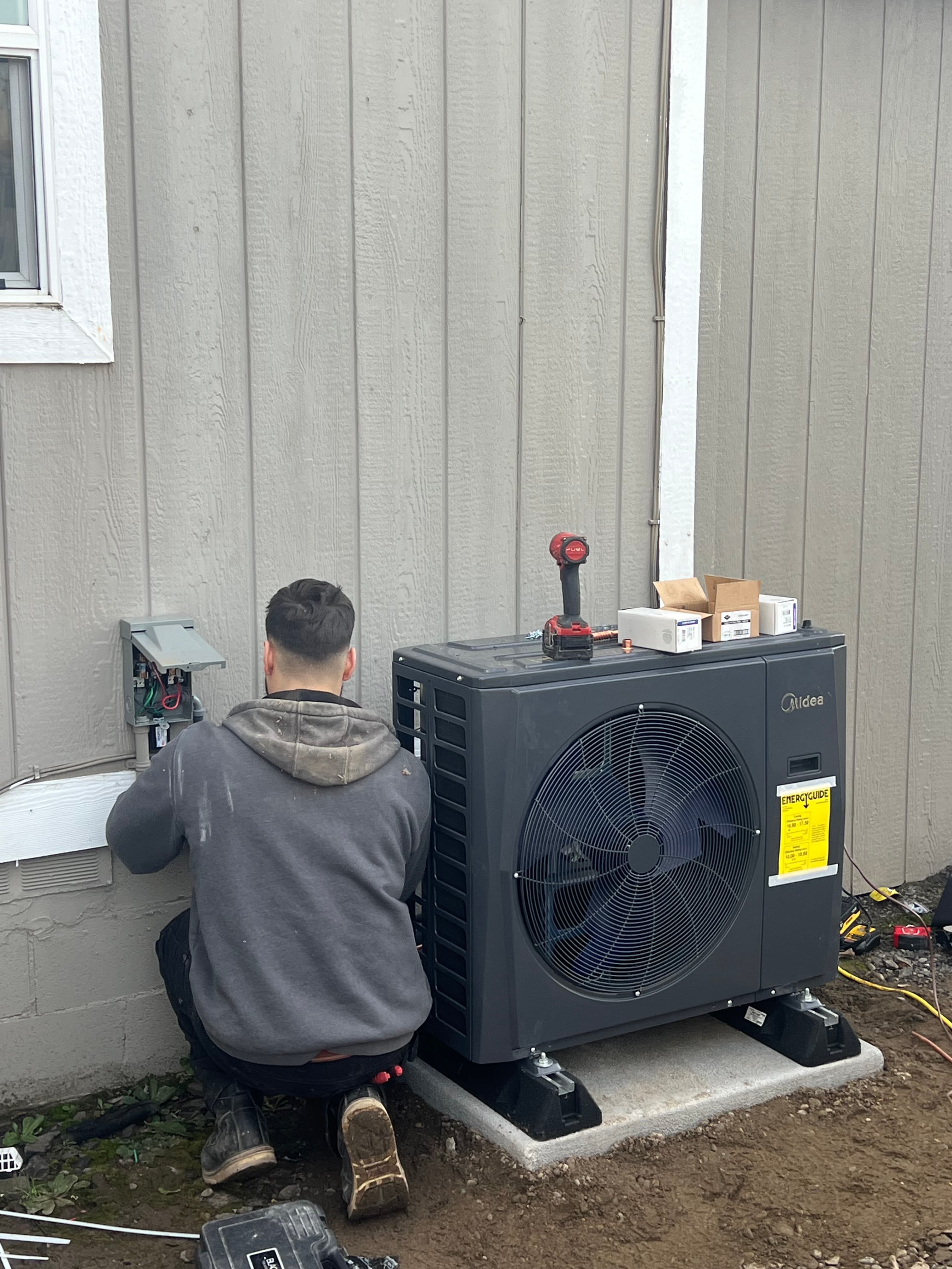 Aztec HVAC technician servicing an outdoor heat pump unit